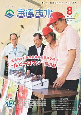 前面部分にルビーロマンのポスターが貼られた茶色の横長机の上に置かれている箱入りのルビーロマンの出来に満足そうに微笑む4人の関係者らの写真を全面に載せた広報宝達志水平成28年8月号の表紙