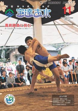 蓮華山相撲場で行われた宝達志水町子供相撲大会で多くの観客が見守る土俵際で男児が脇を持たれながらも相手男児のまわしを両手で掴んで放り投げる瞬間の写真を全面に載せた広報宝達志水平成28年11月号の表紙