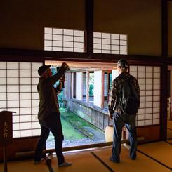 和室内でカメラを上に向けて撮影している人とそれを見ている人の写真
