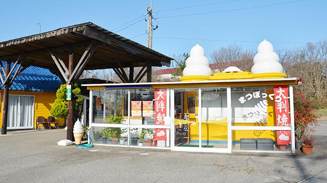 ソフトクリームのオブジェを屋根に乗せた、ガラス張りの小屋の写真