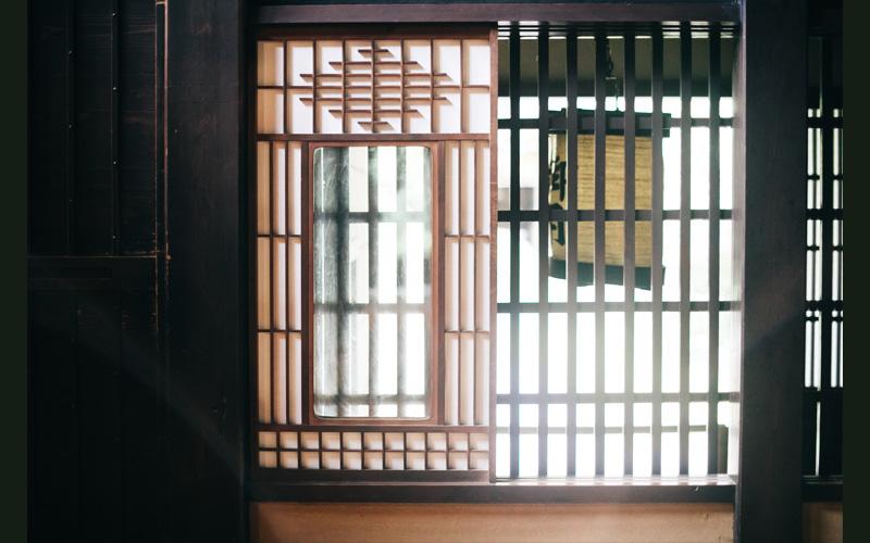 柵と障子で仕切られた反対側で提灯が吊るされている写真