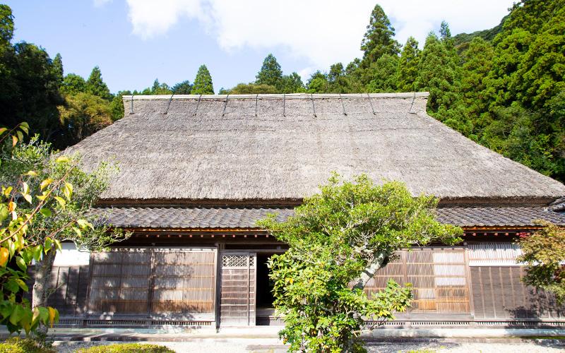 かやぶき屋根の住宅と庭の木が一緒に写っている写真