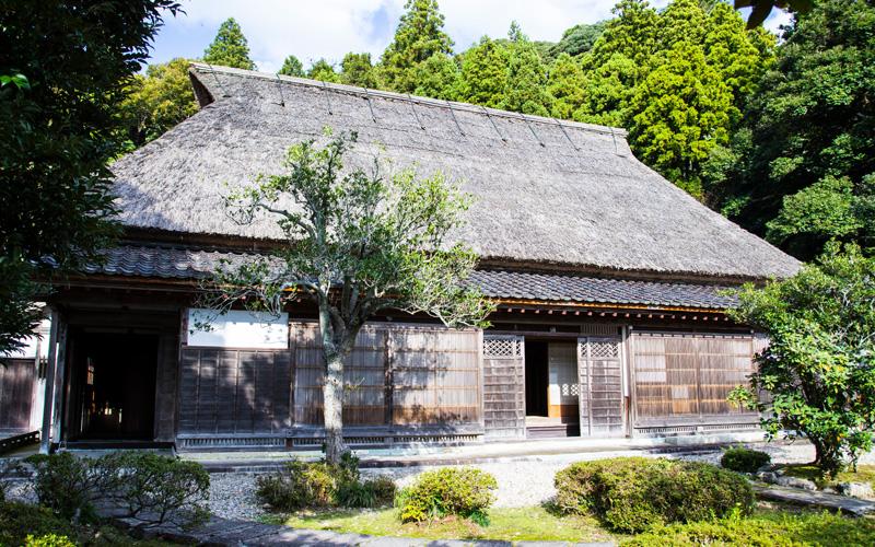 かやぶき屋根の住宅と手前の庭を左斜め前から撮影した写真