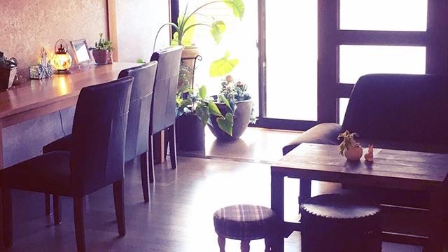 テーブルや椅子が置かれ、観葉植物や小物が飾られた店内の写真