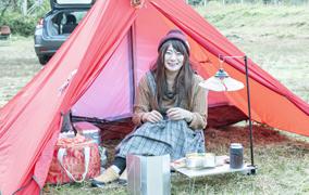 平地にテントやキャンプ道具を広げている女性の写真(宝達志水町のサイトへリンク)