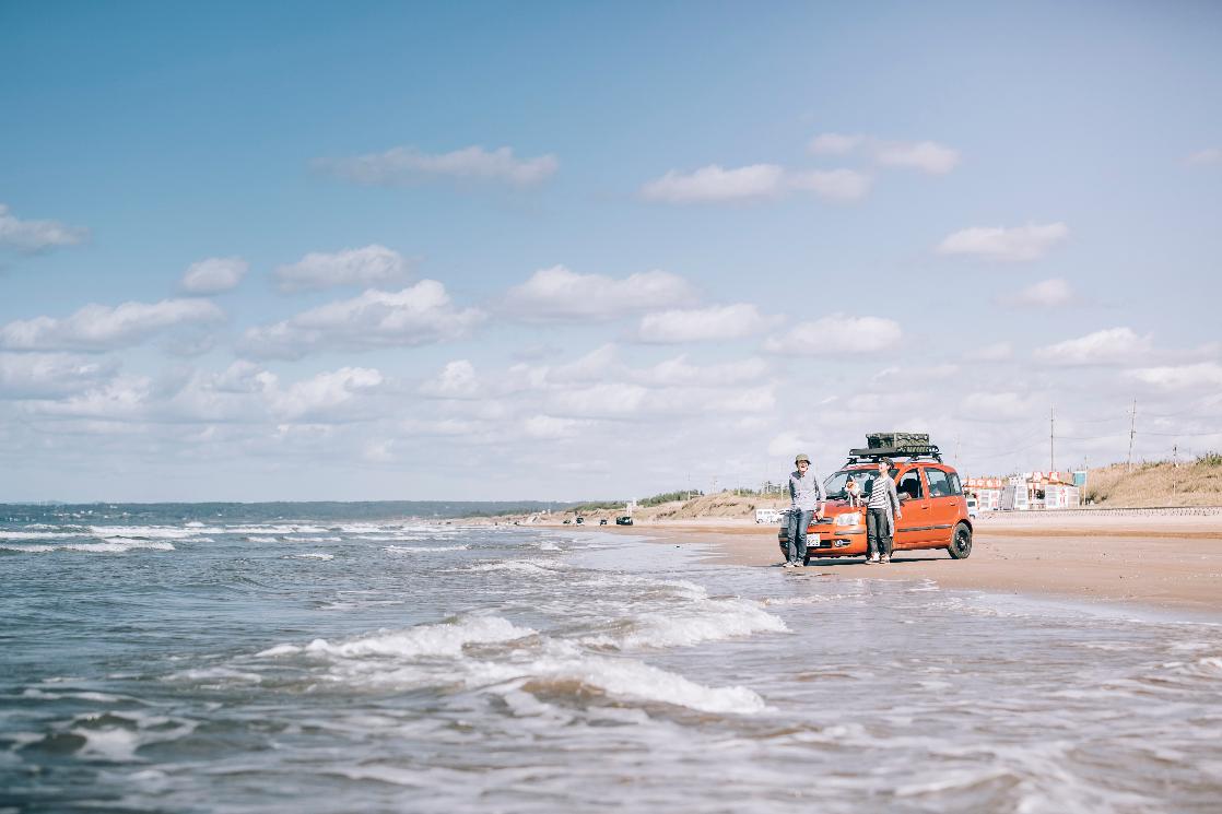 海岸の砂浜でたたずむ人と車
