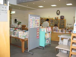 さくらドーム21館内にある宝達志水町立図書館のカウンターで手続きをする来館者の男性と司書の女性を男性の背中側から撮影した写真