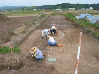 帽子をかぶった4名の調査員が発掘調査をしている写真