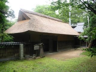 生い茂る木々の中に建っている国指定重要文化財喜多家住宅 (表門)を写した写真