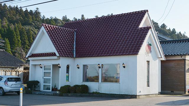 白い壁にリンゴの絵が描かれた、一戸建ての喫茶店の外観の写真