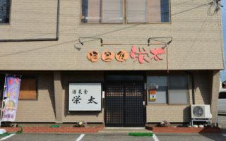 駐車場から店名の栄太が飾られた建物の壁を映した写真