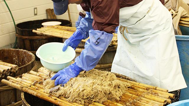 木製のすだれの上で、材料を混ぜる作業をしている人の写真