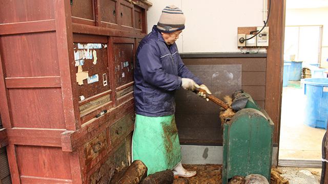 機械の中に、原料の木を入れる作業をしている人の写真