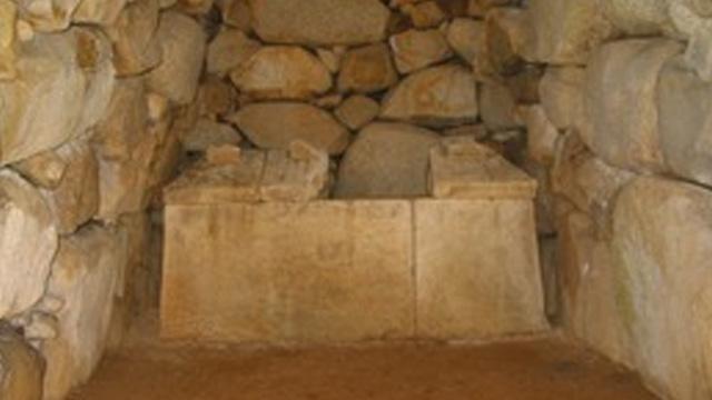 石の積まれた壁に囲まれた、石でできた棺の写真