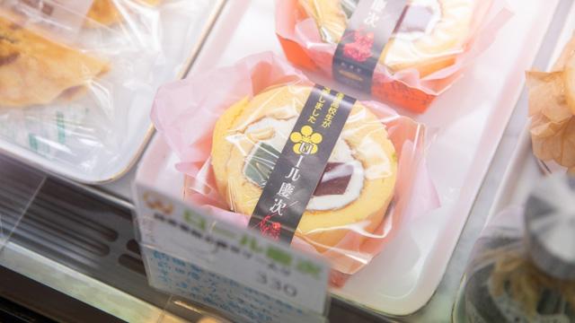 ショーケースに、緑と茶色の具材を包んだロールケーキが並んでいる写真