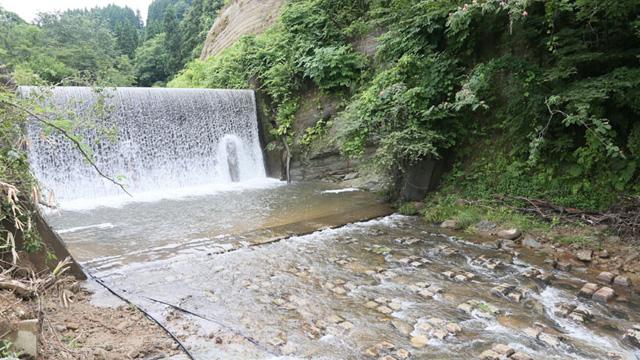 山の中に、人工的な大きな滝と川の流れがある写真