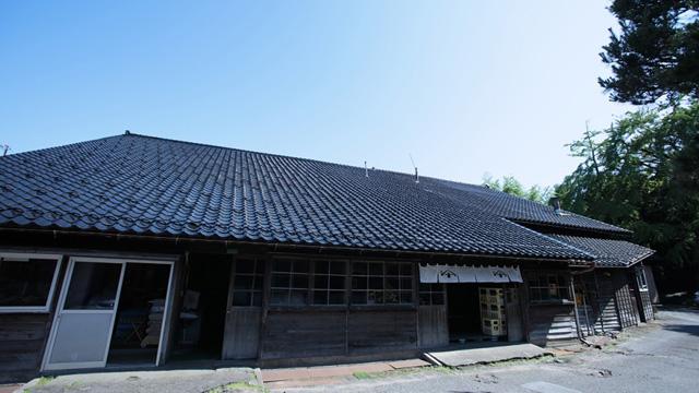 黒い瓦屋根と木の壁の大きな平屋の写真