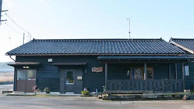 黒い瓦屋根と木の壁でできた、平屋の和風建築の外観の写真