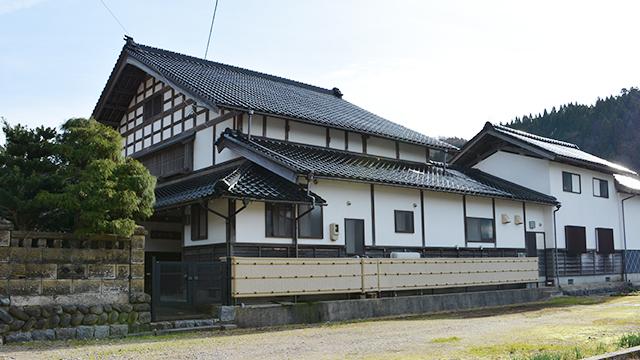 黒い瓦屋根と白い壁の、大きな和風の建物の写真