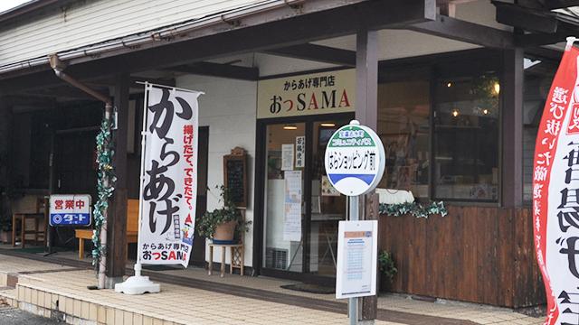 バス停の後ろに、から揚げののぼりを立てた店舗が営業している写真