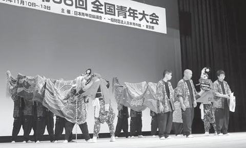 舞台の上で獅子舞を披露するメンバーたちの白黒の写真