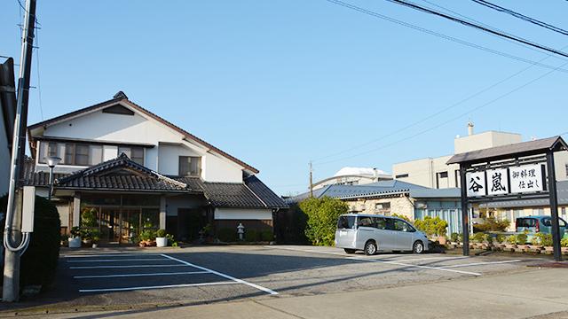 駐車場のある、瓦屋根の二階建ての飲食店の写真