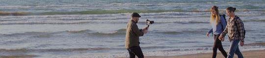 海岸を歩いている2人とそれを撮影している人の写真(千里浜なぎさドライブウェイへのリンク)